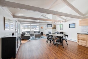 A spacious living area with a dining table and chairs, a sofa, and a kitchen area with a countertop and cabinets.