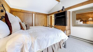A bedroom with a bed, wooden walls, a television, and a window with a view. - Gorgeous country escape with deck & wood-burning fireplace -  near hiking trails (Jackson)