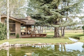 Eine Lodge mit Terrasse, Sitzgelegenheiten im Freien und einem Teich.