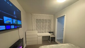A bedroom with a bed, a desk, a chair, a TV mounted on the wall, and a door. - 3 bedroom spacious private basement suite (Langley)