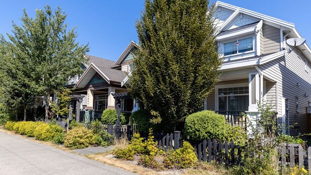 A row of two-story houses with a picket fence, a driveway, and a clear blue sky. - 3 bedroom spacious private basement suite (Langley)