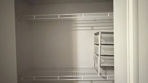 A storage closet with metal shelving units and a white door. - 3 bedroom spacious private basement suite (Langley)