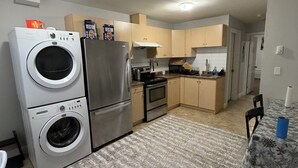 A compact kitchen with a washing machine, refrigerator, microwave, and oven. - 3 bedroom spacious private basement suite (Langley)