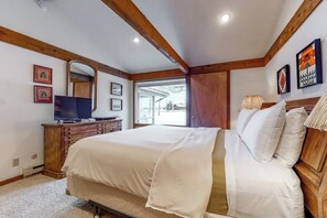 A bedroom with a large bed, wooden headboard, a dresser, a television, and framed pictures on the wall. - Amazing townhouse next to golf course with deck (Jackson)