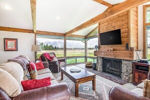 A cozy living room with a fireplace, leather furniture, and a large window offering a mountain view. - Amazing townhouse next to golf course with deck (Jackson)