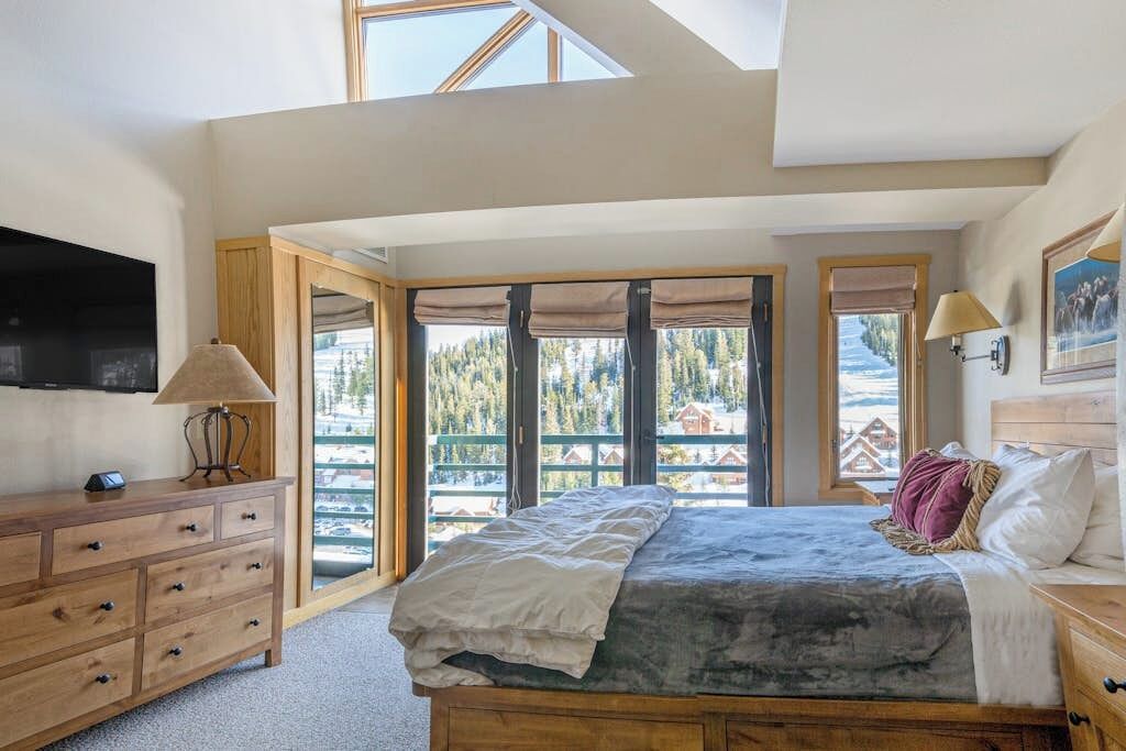 Une chambre à coucher avec un lit, une commode, une lampe et un téléviseur.