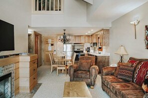 Ein großzügiger Wohnbereich mit Kamin, Fernseher, Sofa und Esstisch mit Stühlen.