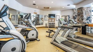 A gym with treadmills, weight machines, and a stone wall. - Ski-in/out, mountain-view condo with hot tub, pool & gym (Big Sky)