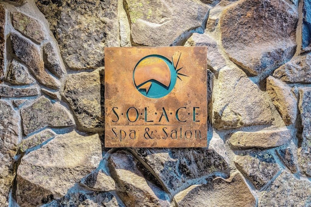A stone wall with a sign for 'SOLACE Spa & Salon' featuring a stylized sun and moon logo.