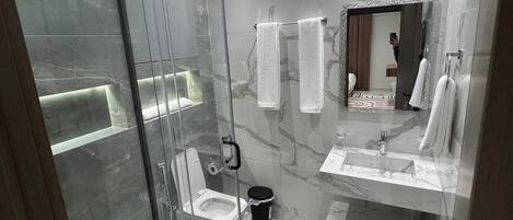 Ein modernes Badezimmer mit einer einteiligen Duschkabine, Toilette, Waschbecken und Spiegel.