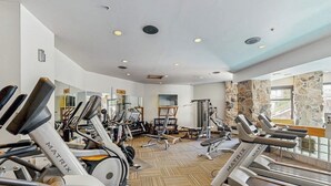 A gym with treadmills, elliptical machines, and weight equipment. - Ski-in/ski-out ski chalet w/shared hot tub, pool, balcony, WiFi, central A/C (Big Sky)