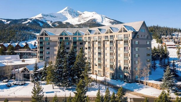 A multi-story hotel with a ski slope in the background. - Ski-in/ski-out ski chalet w/shared hot tub, pool, balcony, WiFi, central A/C (Big Sky)
