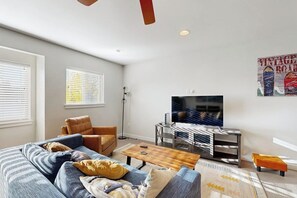 A living room with a sofa, armchair, coffee table, TV, and artwork on the wall. - Immaculate Condo Near Meadow Village | New Carpet, Mountain Views & Dog-Friendly (Big Sky)