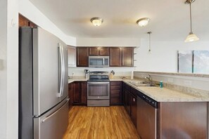 Eine moderne Küche mit Edelstahlgeräten, Holzschränken und einer Arbeitsplatte aus Granit.