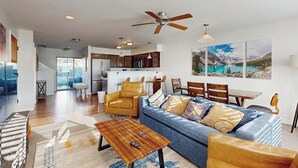 A modern living room with a sofa, coffee table, and chairs, a kitchen in the background, and a dining area with a table and chairs. - Immaculate Condo Near Meadow Village | New Carpet, Mountain Views & Dog-Friendly (Big Sky)