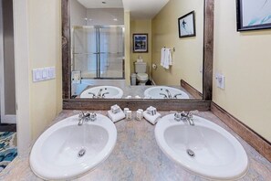 Une salle de bain avec deux lavabos, une douche et des toilettes.