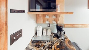A kitchen with a microwave, coffee maker, and storage jars labeled coffee, sugar, and tea. - Modern duplex with gas fireplace, free WiFi, & walkable downtown location (Bozeman)