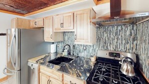 A kitchen with wooden cabinets, a stainless steel refrigerator, a gas stove, and a tiled backsplash. - Modern duplex with gas fireplace, free WiFi, & walkable downtown location (Bozeman)