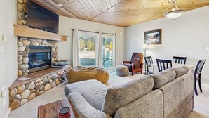 Un salon doté d’une cheminée en pierre, d’un plafond en bois et d’un grand canapé.