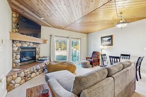 Ein Wohnzimmer mit Kamin aus Stein, Holzboden und einer großen Couch.