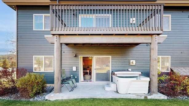 Une maison à deux étages dotée d’un balcon, d’un jacuzzi et d’une terrasse couverte.