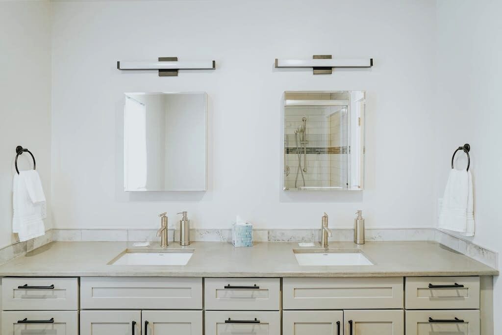 A bathroom with two sinks, a mirror, and a towel rack.