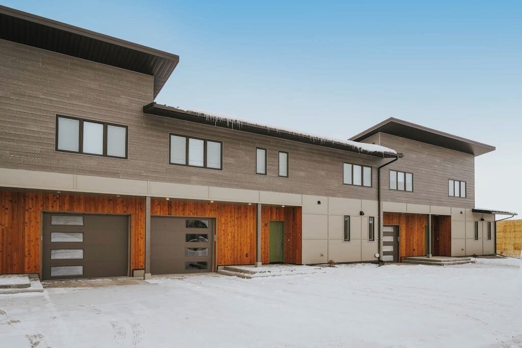 A modern multi-story building with a flat roof, large windows, and a covered entrance area.