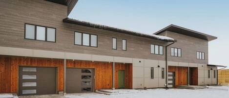 A modern multi-story building with a flat roof, large windows, and a covered entrance area.