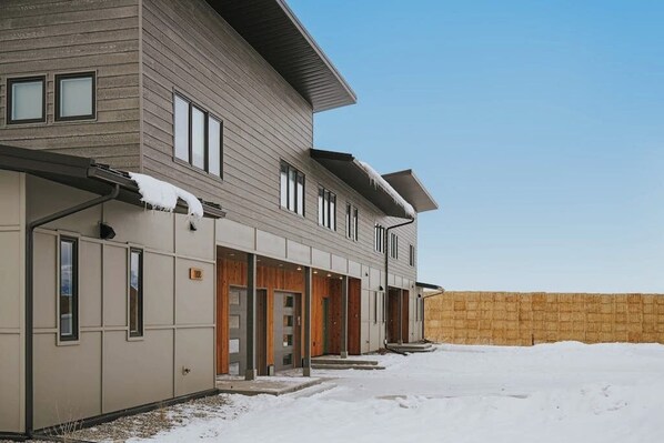 A multi-story building with a flat roof and a covered entrance area.