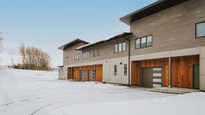 A modern building with multiple garage doors and a flat roof. - Beautiful home near ski resorts with patio, grill, washer/dryer, fast WiFi & AC (Bozeman)