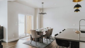 A modern dining area with a large table, chairs, and pendant lighting. - Beautiful home near ski resorts with patio, grill, washer/dryer, fast WiFi & AC (Bozeman)