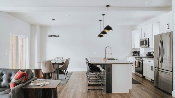 A modern kitchen with white cabinets, stainless steel appliances, and a central island with bar stools. - Beautiful home near ski resorts with patio, grill, washer/dryer, fast WiFi & AC (Bozeman)