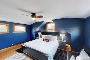 A bedroom with a bed, a ceiling fan, two bedside tables, and a nightstand. - Charming downtown retreat with stained glass, enclosed yard, and washer/dryer (Bozeman)
