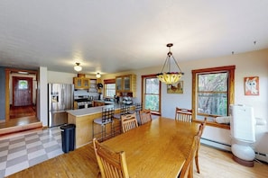 A kitchen with a central island, wooden chairs, a dining table, and a large window. - Charming downtown retreat with stained glass, enclosed yard, and washer/dryer (Bozeman)