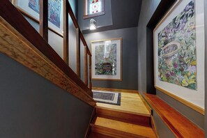 A staircase with wooden steps and handrails, framed artwork on the walls, and a patterned rug at the bottom. - Charming downtown retreat with stained glass, enclosed yard, and washer/dryer (Bozeman)