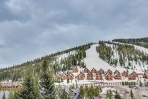 Eine Lodge mit mehreren Holzhäusern, einer Skipiste und einem bewaldeten Berg im Hintergrund.