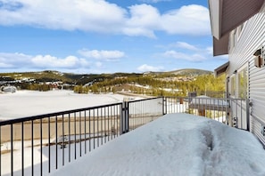 Ein mit Schnee bedeckter Balkon mit Blick auf eine Wohngegend und hügelige Ferne.