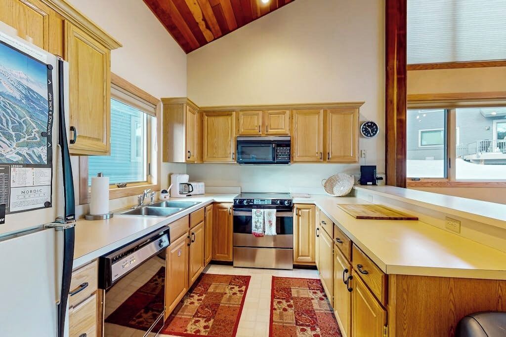Una cocina con gabinetes de madera, estufa, microondas y refrigerador.
