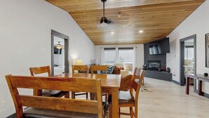 Un espace repas avec une table et des chaises en bois, une cheminée, et une cuisine moderne en arrière-plan.