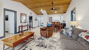 Un vaste espace de vie doté d’un plafond en bois, d’un canapé, d’une table basse et d’une table à manger avec des chaises.