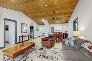 A spacious living area with a wooden ceiling, a sofa, a coffee table, and a dining table with chairs. - Fully Newly Remodeled Big Sky Condo with Mountain & Valley Views Private Hot Tub (Big Sky)