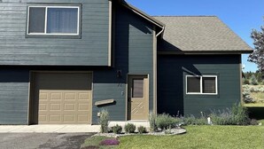 A two-story house with a garage, a front door, and a small side window. - Modern Mountain Getaway with New Hot Tub – Big Sky, Montana (Big Sky)