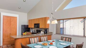 A modern kitchen with wooden cabinets, a central island, and a dining area with a glass table.