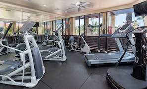 Un gimnasio con cintas de correr, elípticas y bicicletas estáticas.