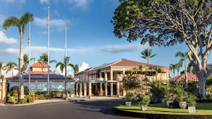 A hotel with a large building, palm trees, and a flagpole.