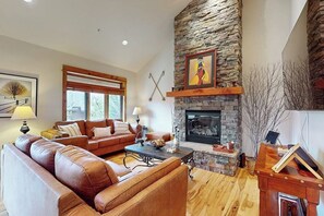 Ein Wohnzimmer mit Kamin aus Stein, einer Ledersofa, einem Holztisch und einem gerahmten Bild über dem Kamin.