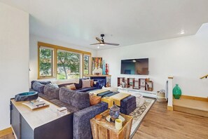 Ein modernes Wohnzimmer mit einer Eckcouch, einem Flachbildfernseher und einem Deckenventilator.