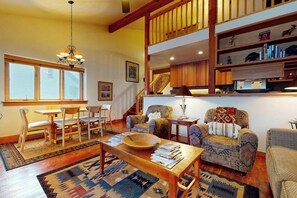 A cozy living room with a dining area, wooden furniture, a staircase, and a bookshelf. - Lovely home with well-equipped kitchen & back deck - walk to shopping & dining (Wilson)