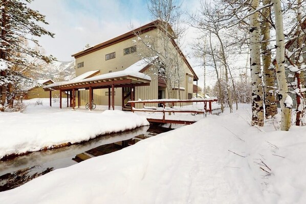 Une maison à deux étages avec un porche abrité et un petit ruisseau qui traverse la cour.