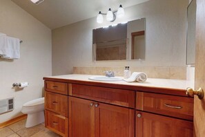 Une salle de bain avec un meuble-lavabo en bois, un évier, un miroir et des toilettes.